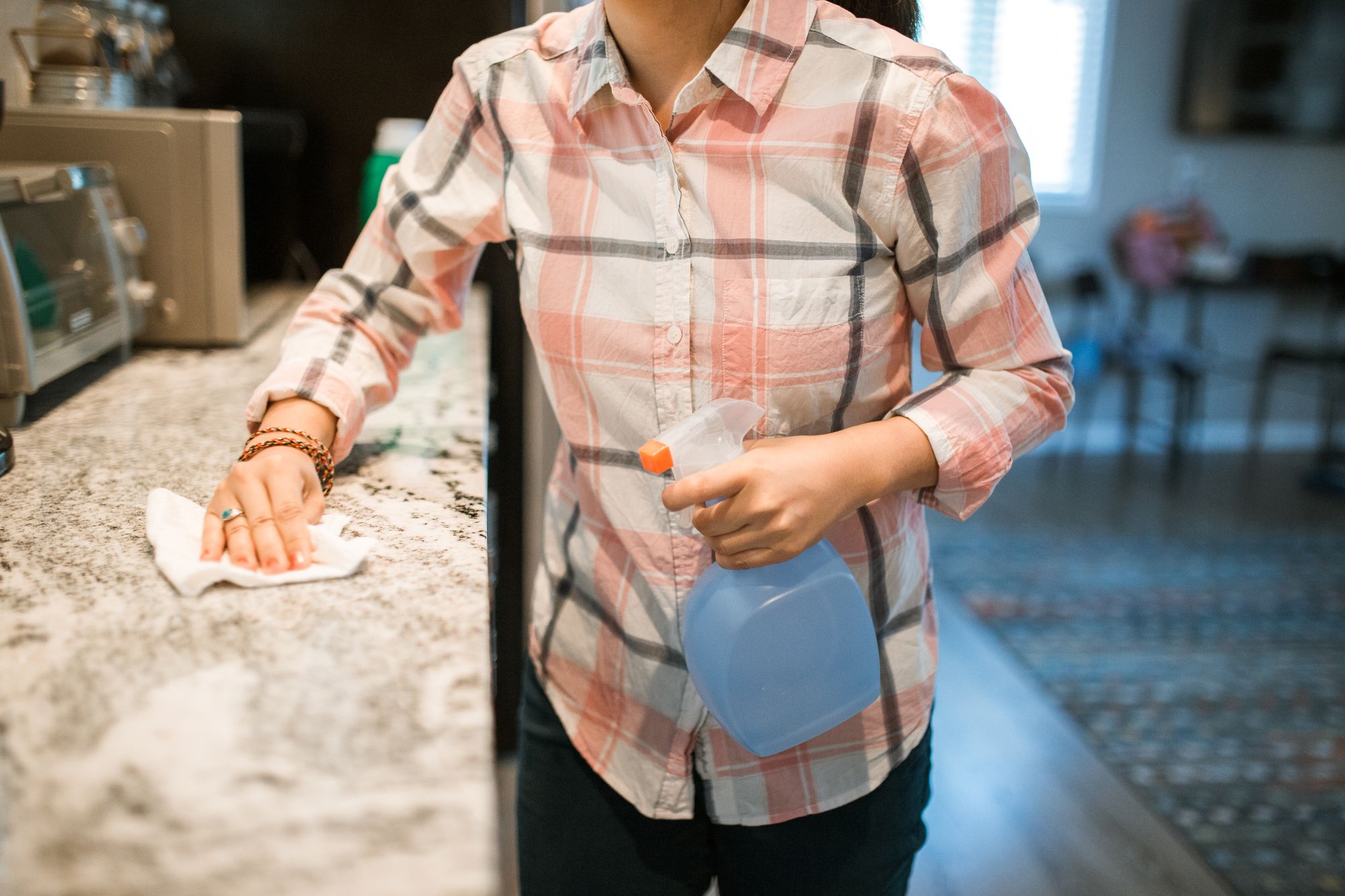 Cleaner wiping a kitchen counter in a bright home